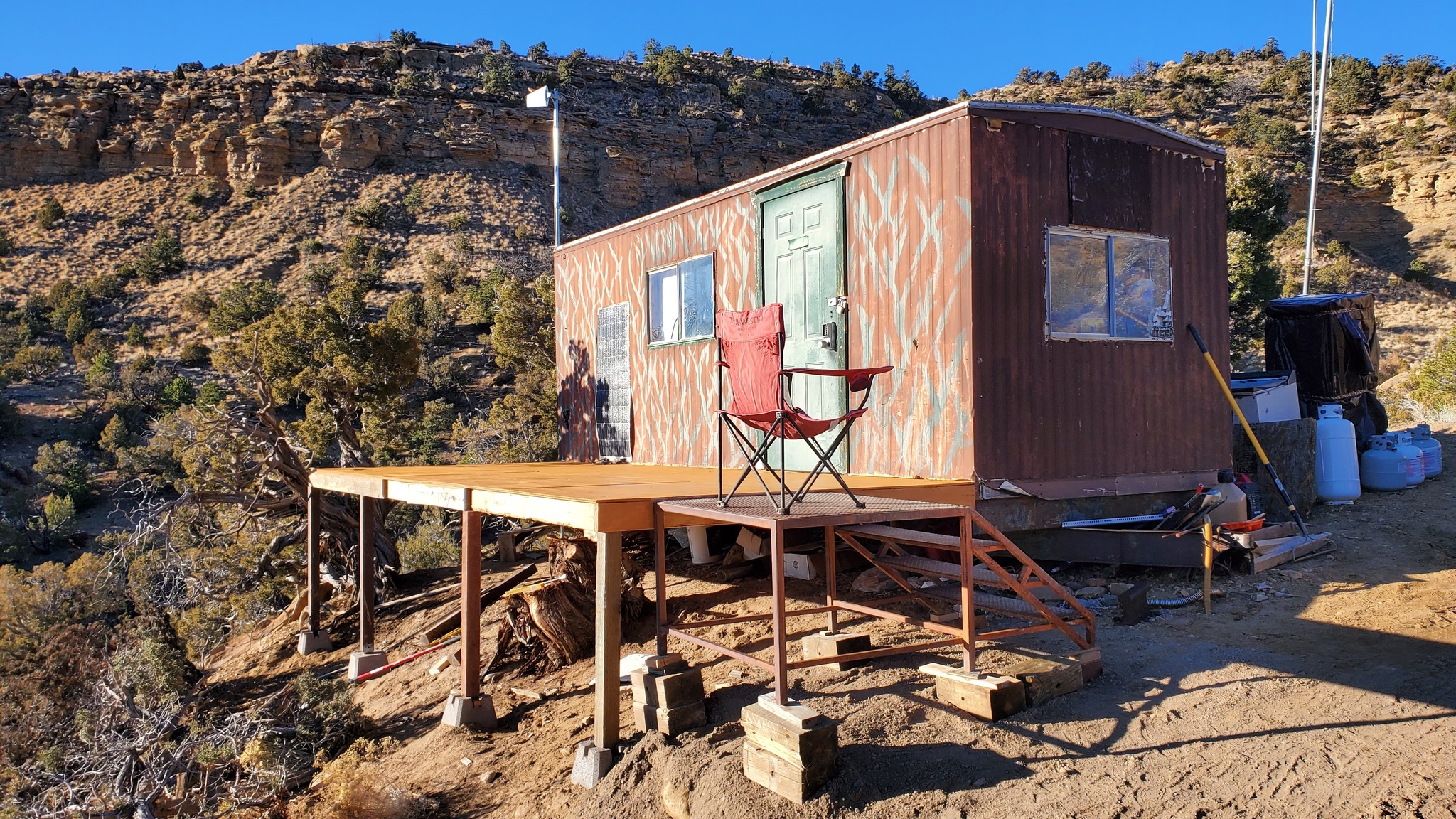 The meme is a photo of a small, rusty, and rundown trailer or "hovel" in a desert-like setting. The image is captioned "My 2023 Goals" and features a small table and chair on the trailer's porch, implying that the person has achieved their goals and is now living in a tiny, self-sufficient home.